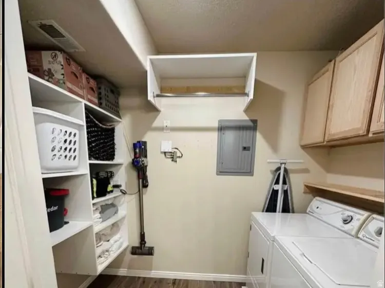 Dedicated laundry area featuring a stacked washer and dryer, wood-finish flooring, built-in shelving, and upper cabinetry