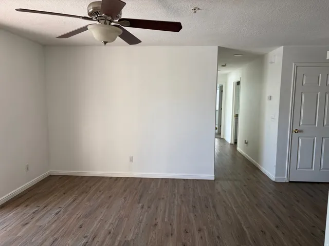 Wood-finish flooring throughout, ceiling fan with integrated lighting, and white paneled doors with gold-tone hardware