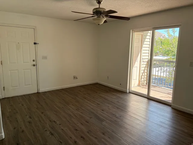 Wood-finish flooring, ceiling fan with integrated lighting, white interior door, sliding glass door, and outdoor balcony with railing