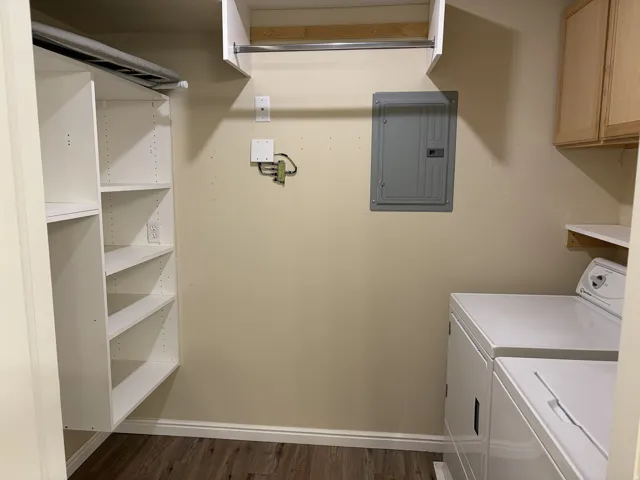 Laundry area with wood-finish flooring, built-in shelving, and upper cabinetry