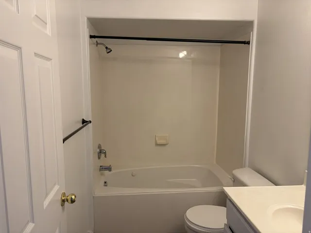 White tub/shower combination with a single-handle faucet, integrated soap dish, and a black shower rod