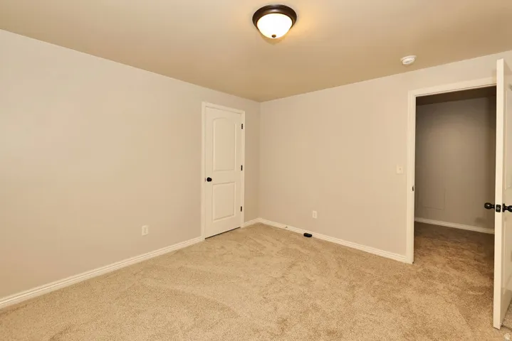 Neutral wall paint, plush carpeting, white baseboards, and two-panel interior doors with dark hardware
