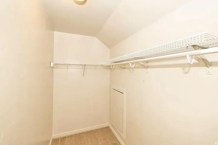 Spacious walk-in closet featuring dual clothing rods, wire shelving system, and neutral carpeting—ideal for ample storage and organization