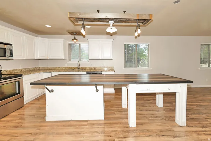 Open-concept kitchen featuring white cabinetry, light-toned countertops, and wood-finish flooring