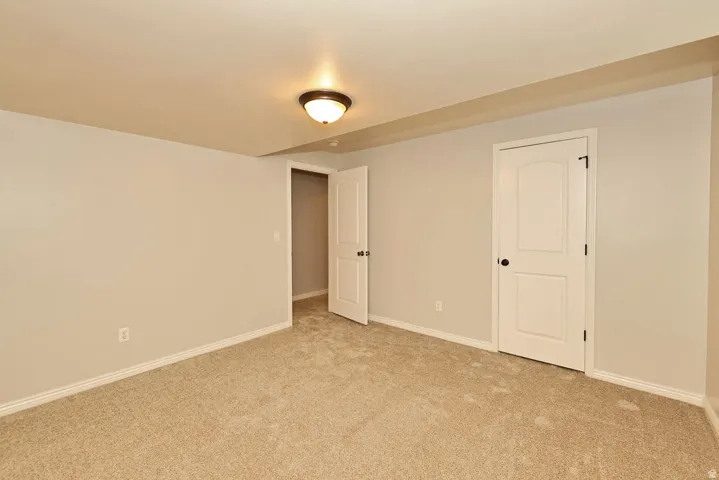 Spacious bedroom featuring neutral wall finishes, carpet flooring, and abundant natural light from a ceiling-mounted fixture