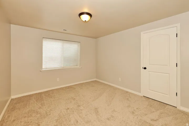 Neutral-toned room with plush carpeting and a single window featuring blinds
