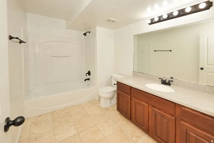 Spacious primary bathroom featuring a wood-finish vanity with dual sinks, quartz countertop, and brushed nickel fixtures
