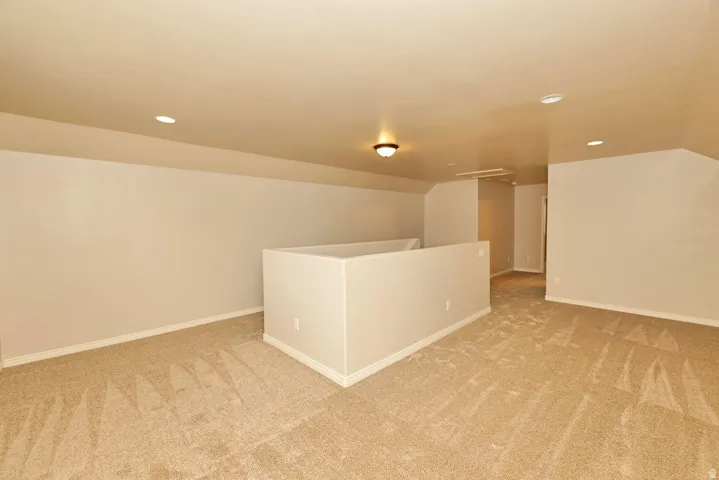 Spacious basement featuring engineered wood-finish flooring, recessed ceiling lights, and a central built-in partition wall
