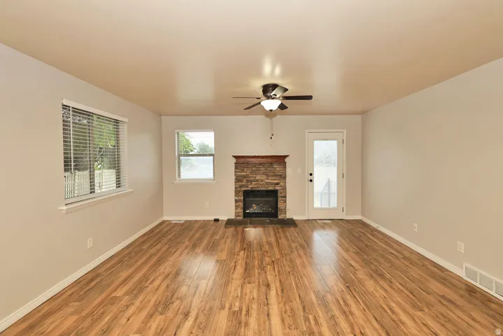 Spacious living room showcasing gleaming wood-finish flooring, neutral wall finishes, and abundant natural light from multiple windows