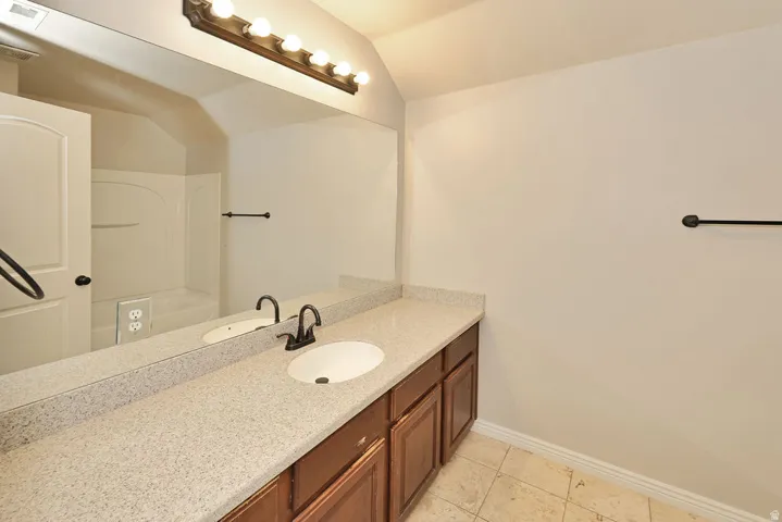 Bathroom featuring a double vanity with an integrated white sink, a light-colored speckled countertop, and dark wood cabinetry
