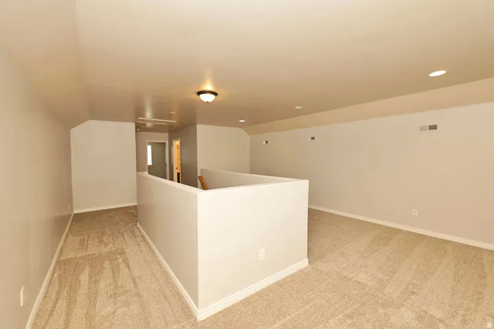 Open loft area featuring neutral-toned carpet flooring