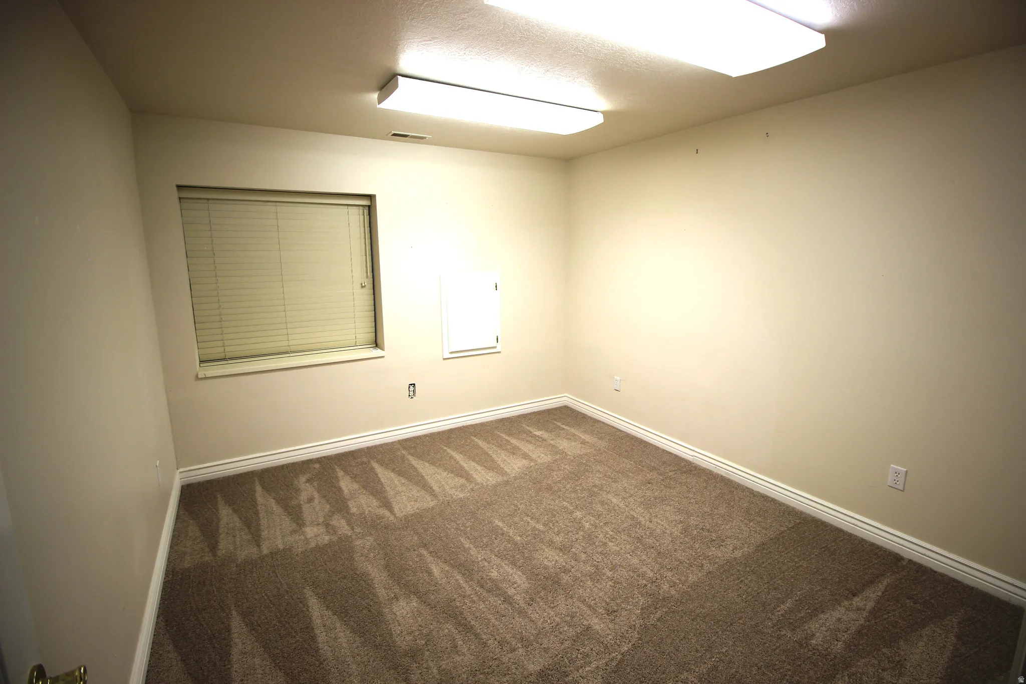 Wall-to-wall carpeting with a geometric pattern and window with blinds