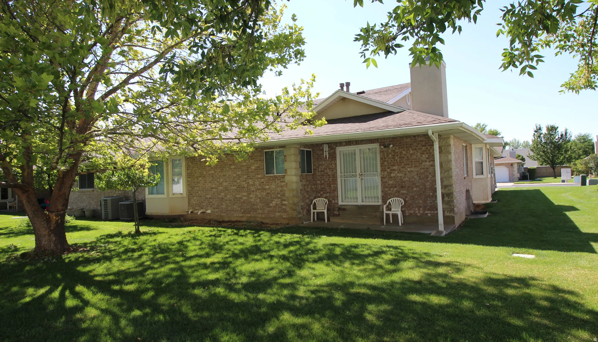 Rear exterior showcasing a brick facade and a covered patio with sliding glassRear view with covered patio and french  doors from family room.