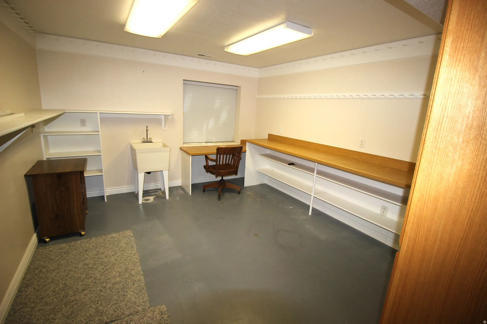 Exercise Room or Hobby Room  featuring a built-in workstation with wood-finish countertop, a utility sink, and recessed shelving