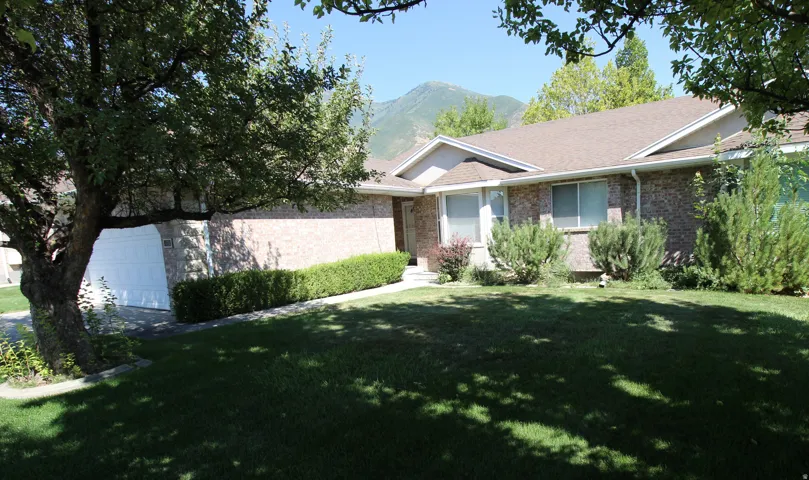 Brick exterior residence featuring a front lawn and mature trees