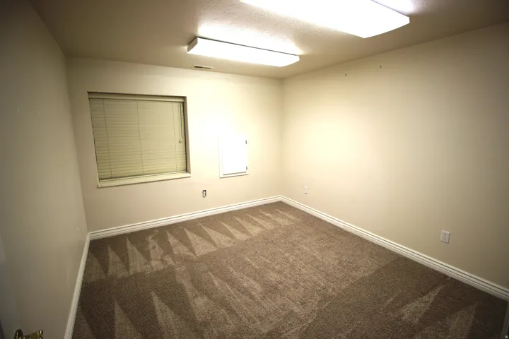 Wall-to-wall carpeting with a geometric pattern and window with blinds