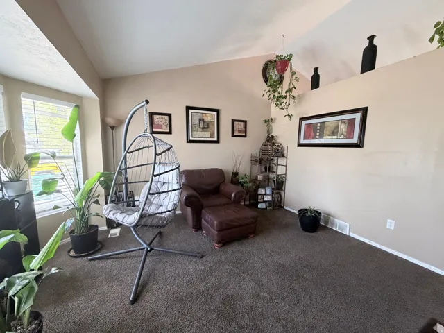 Living area featuring vaulted ceilings, a large bay window, and neutral wall tones