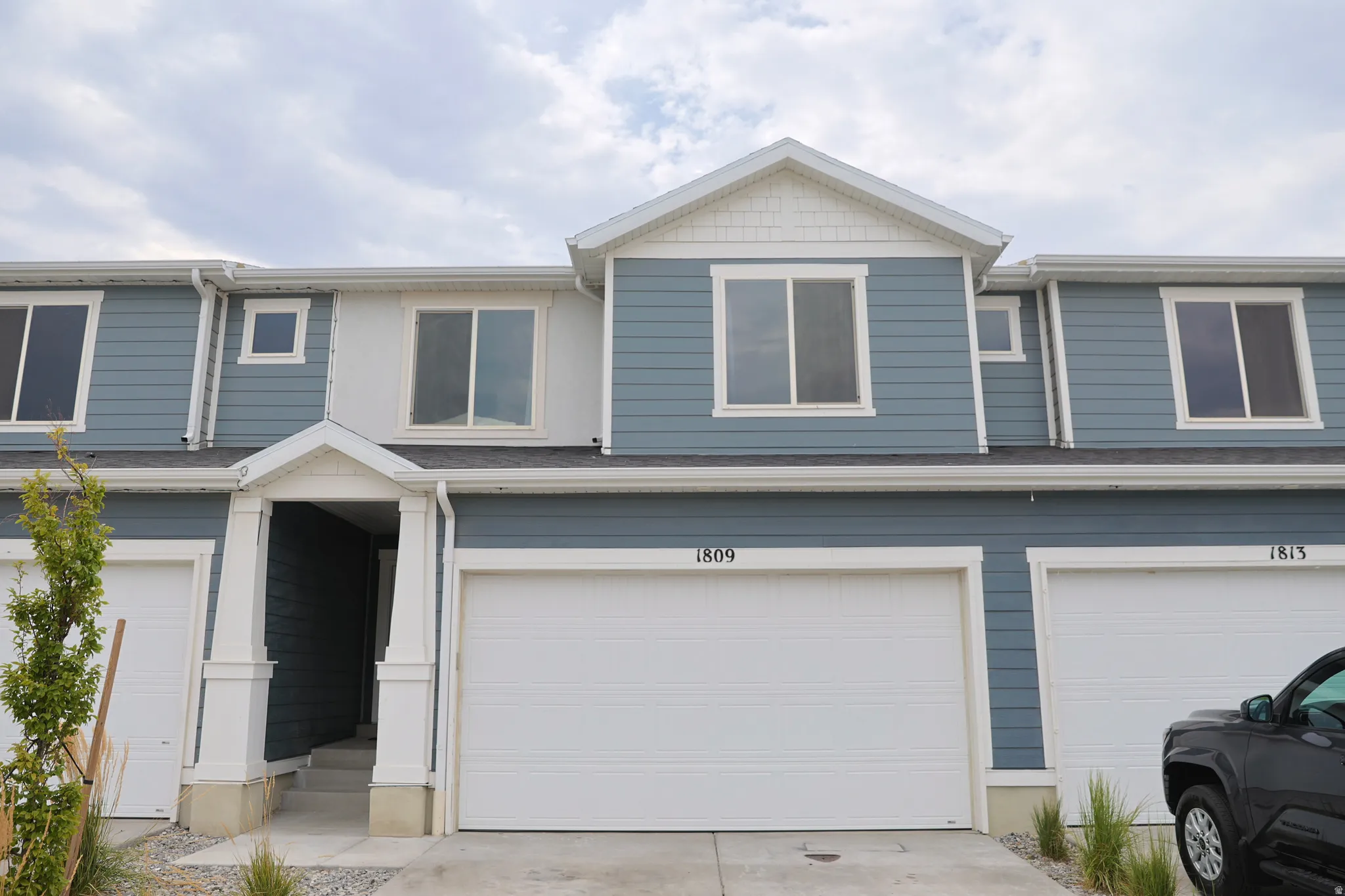 Multi-level townhome-style residence featuring blue siding, white trim, and a prominent front entry with a covered porch