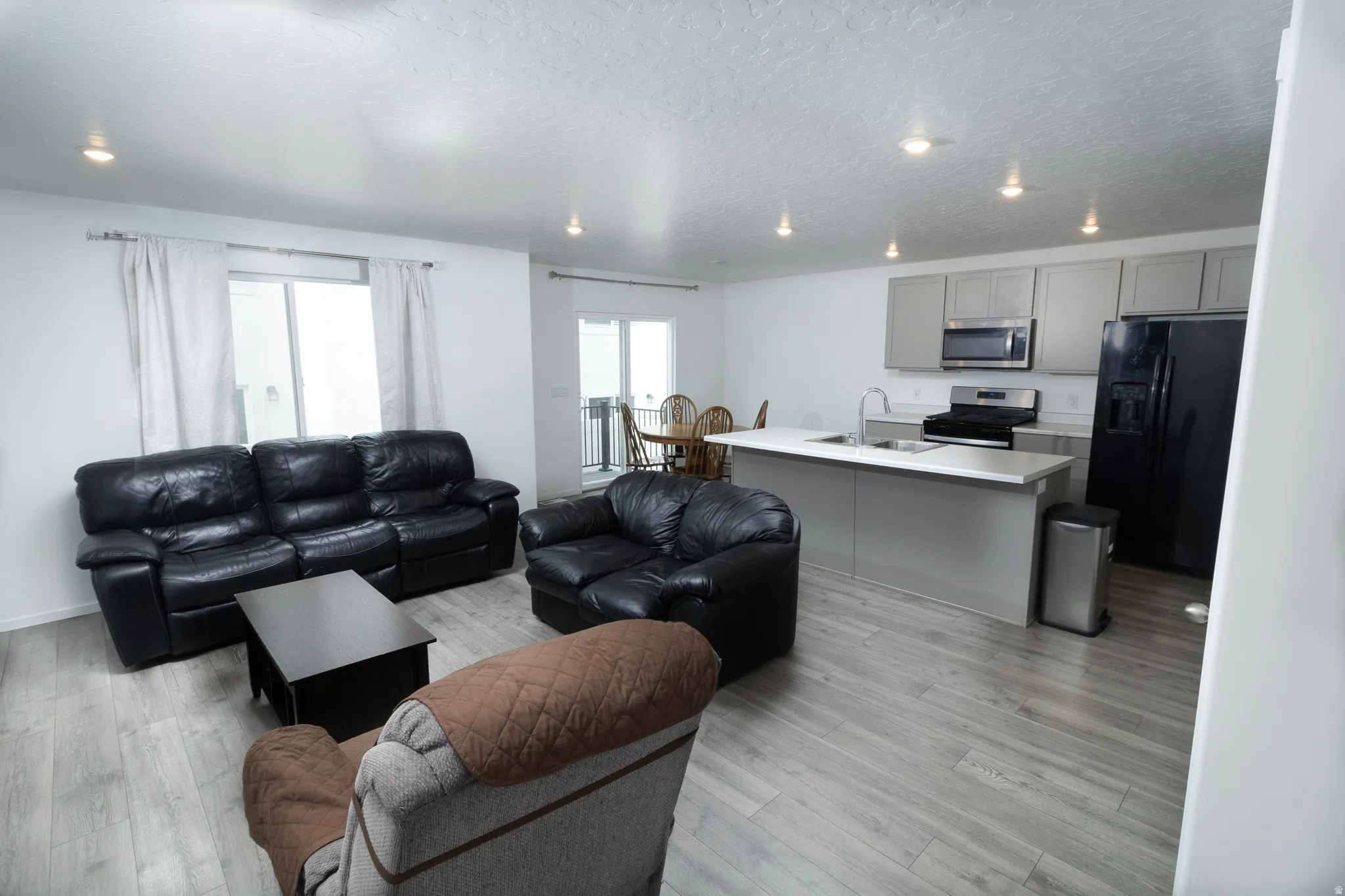 Open-concept living space with wood-finish flooring, recessed lighting, and a modern kitchen