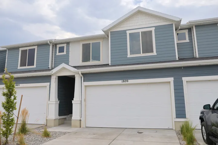 Two-story townhome with blue siding, white trim, and a prominent front entry with white columns