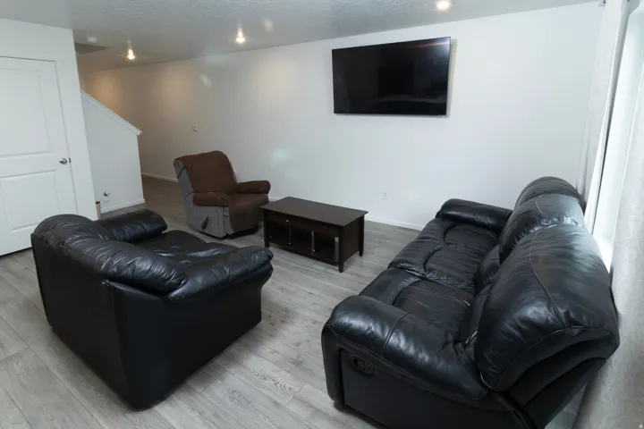 Spacious room featuring wood-finish flooring, recessed lighting, and a wall-mounted display
