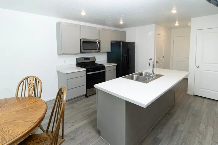 Kitchen with light gray cabinetry, white countertops, a stainless steel sink, and wood-finish flooring