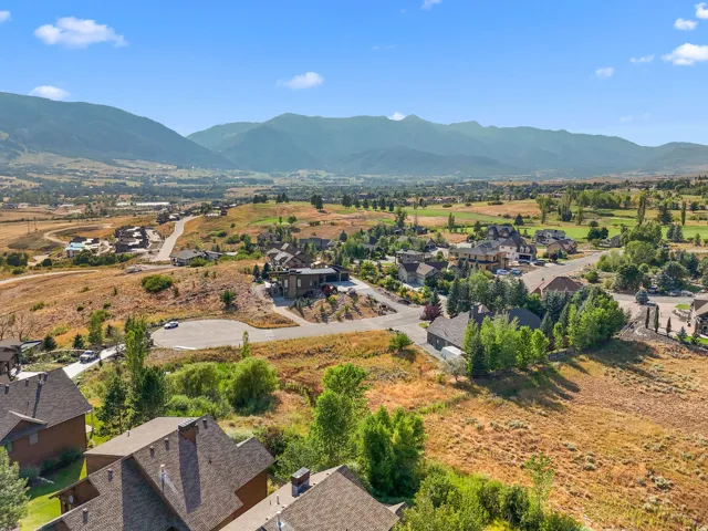 Expansive valley with mountain backdrop featuring scattered residential properties, mature trees, and a distant golf course