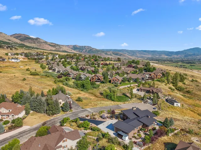 Expansive residential community nestled on a gentle hillside, surrounded by natural mountainous terrain and distant green valleys