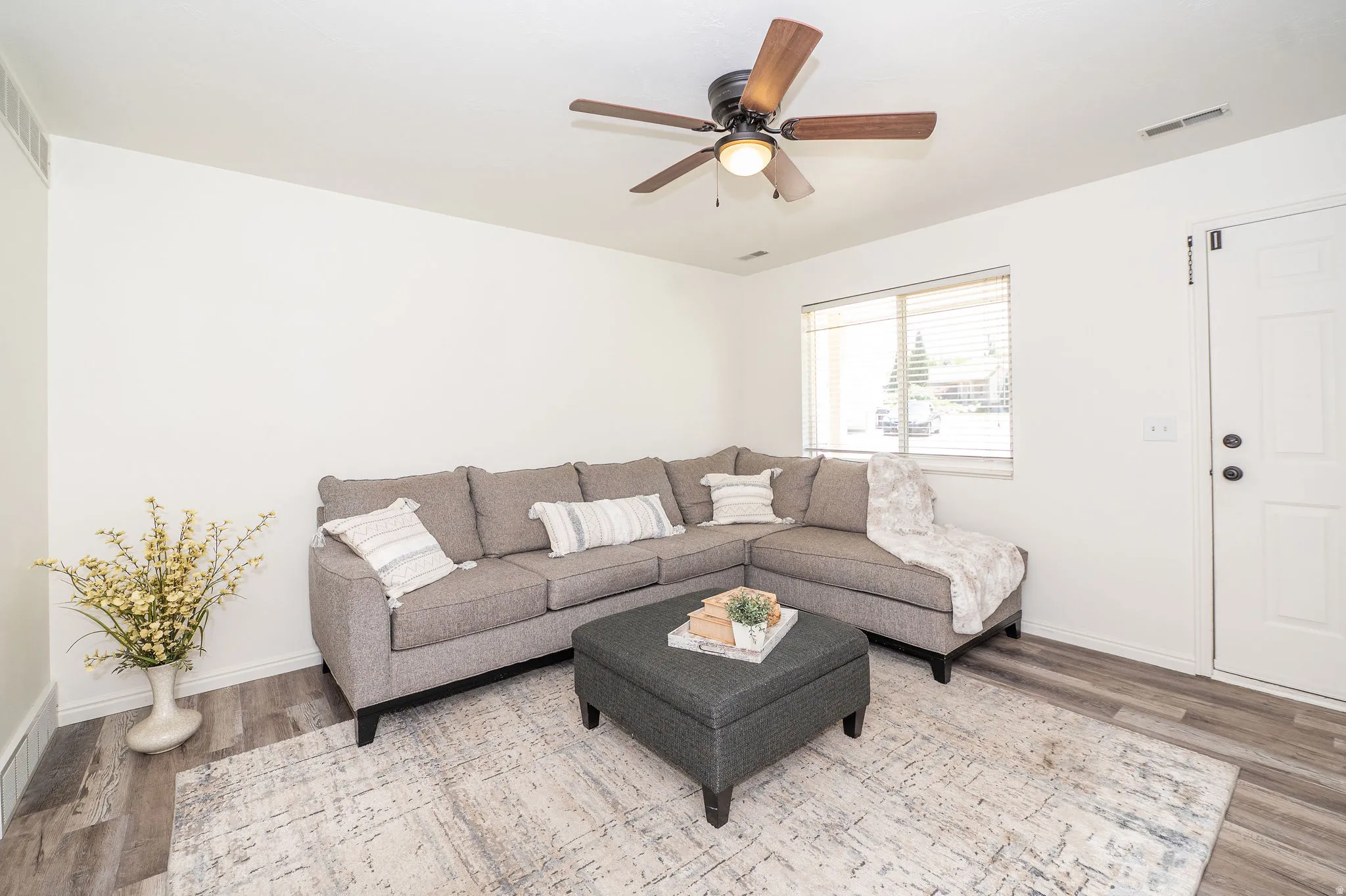 Living room with LVP flooring, fresh paint, and a ceiling fan.