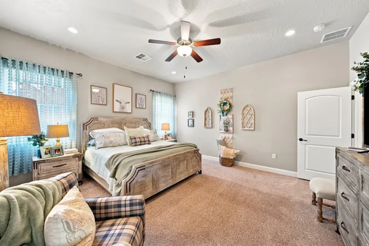 Spacious room featuring carpeting, neutral wall tones, a ceiling fan with integrated lighting, recessed lighting, and a white arched panel door with matte black hardware