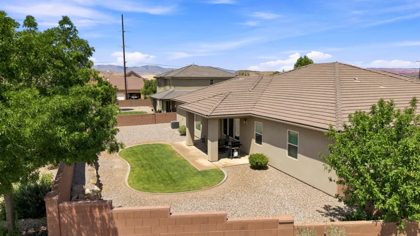 Rear exterior featuring a covered patio, a shaped lawn area, and a gravel landscape