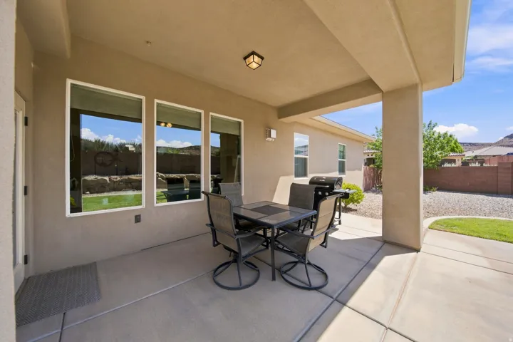 Covered concrete patio with stucco exterior and three large windows