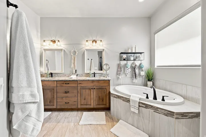 Dual vanity with wood-finish cabinetry, light-toned countertop, and undermount sinks