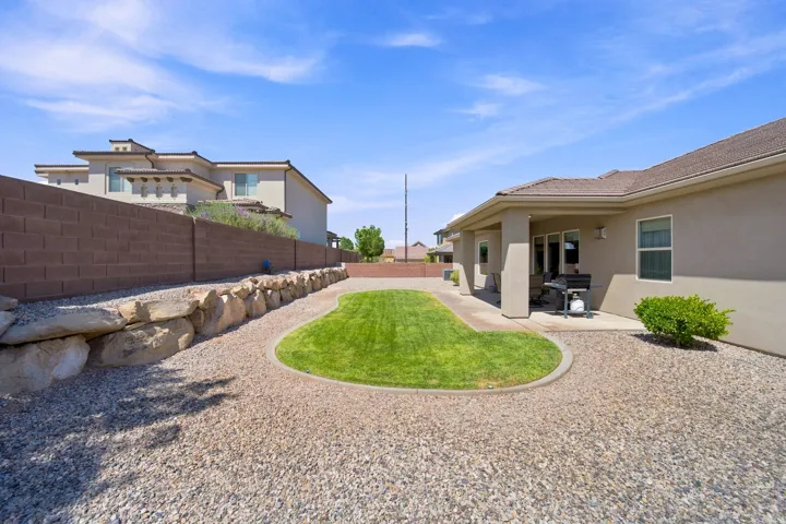 Expansive backyard featuring a central manicured lawn bordered by decorative gravel