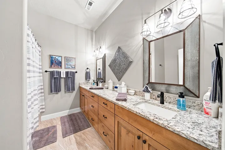 Double vanity with granite-style countertop and wood-finish cabinetry
