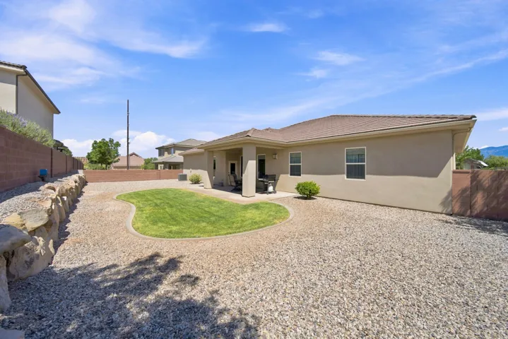 Expansive backyard featuring a central shaped lawn, extensive gravel landscaping, and a low stone retaining wall