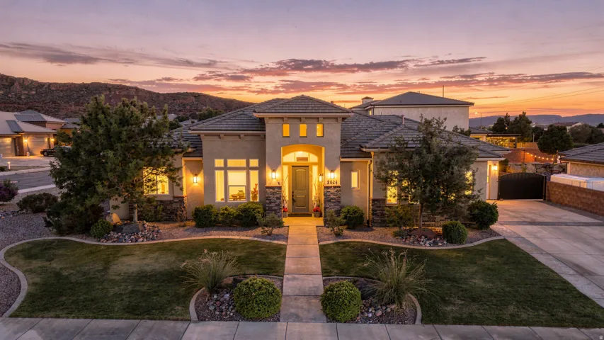 Stucco exterior featuring stone accents, a covered entry, and a paved walkway