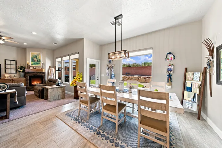 Spacious dining area featuring wood-finish flooring, a contemporary linear chandelier, and ample natural light from a large window