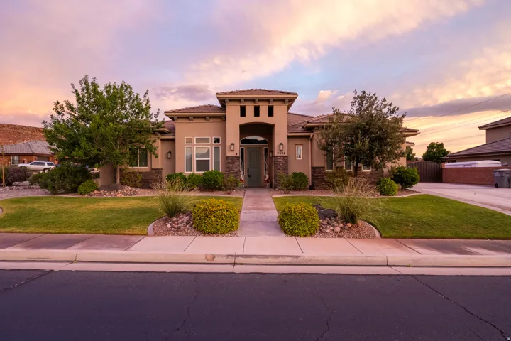 Stucco exterior with stone accents, featuring a prominent arched entryway and a paver walkway