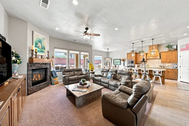 Spacious living area featuring a stone-clad fireplace with a wood mantle, recessed lighting, and large windows
