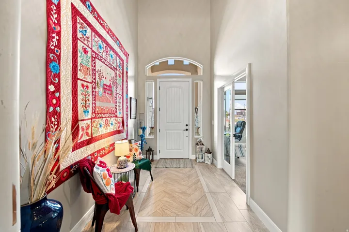 Entryway featuring a high vaulted ceiling, arched transom window, wood-finish flooring with a decorative inlay, and a white paneled front door