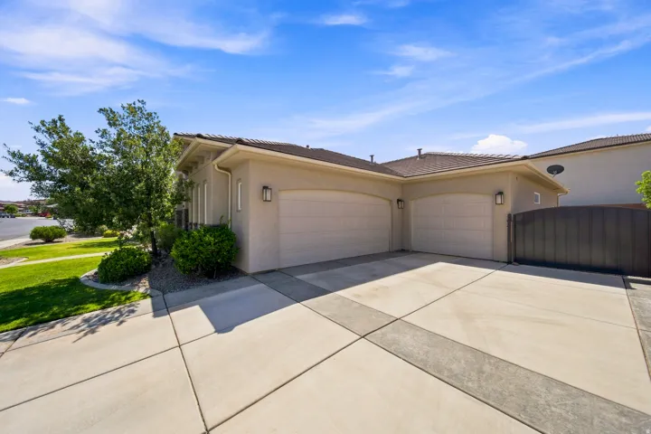 Stucco exterior featuring a two-car garage, concrete driveway with decorative accents, and a privacy fence