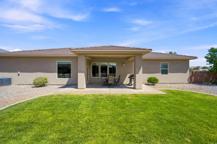 Expansive rear yard featuring a covered patio, a manicured lawn, and a gravel perimeter