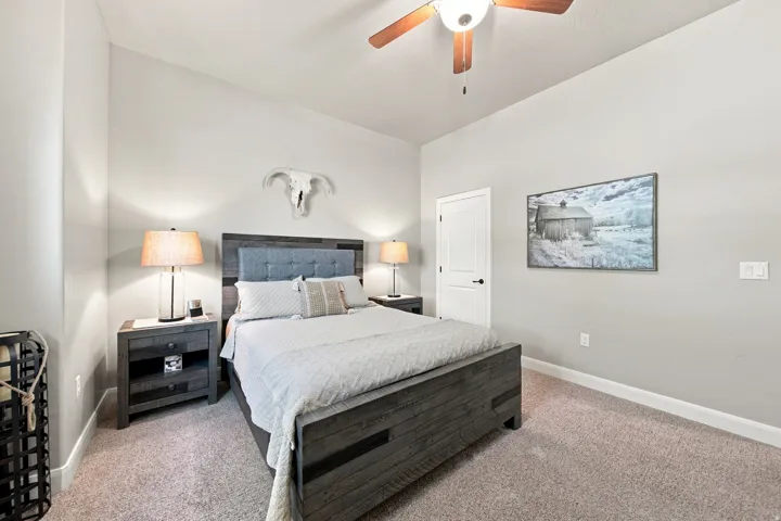 Spacious room with a neutral color palette, ceiling fan, carpet flooring, a white interior door with black hardware, and white baseboards