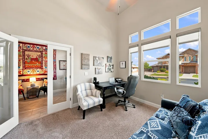 Room with vaulted ceiling, carpet flooring, multiple windows, and french doors