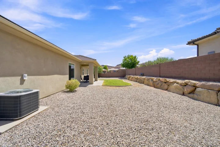 Expansive backyard featuring a gravel landscape, a manicured lawn area, and a large stone retaining wall