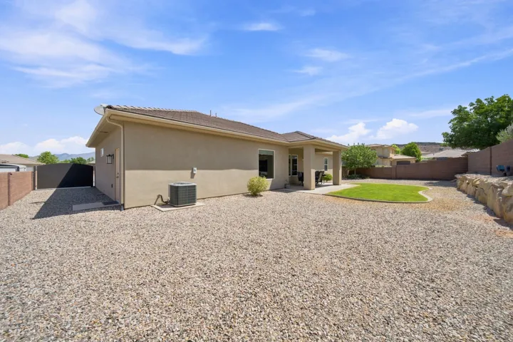 Expansive backyard featuring a large gravel area, a shaped lawn patch, and a covered patio