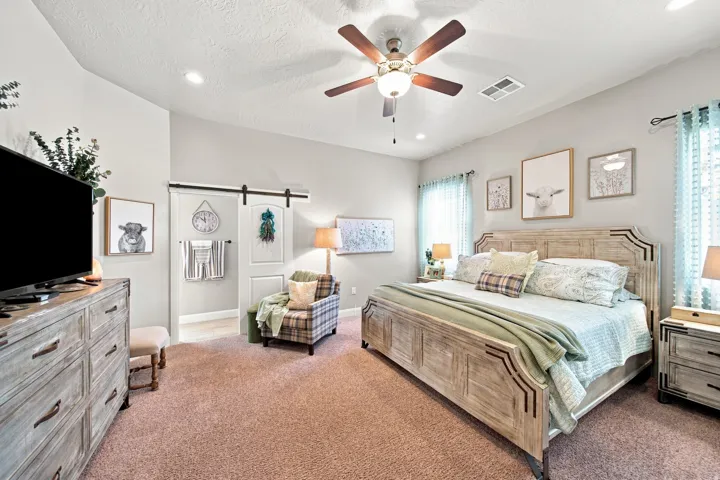 Spacious bedroom featuring light neutral wall tones, recessed lighting, and a ceiling fan
