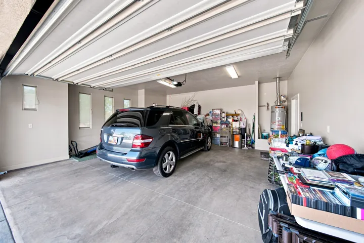 Spacious garage featuring a concrete floor, multiple windows providing natural light, and overhead fluorescent lighting