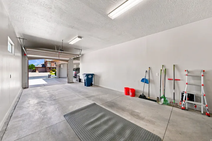 Spacious garage featuring a concrete floor, white painted walls, and overhead fluorescent lighting